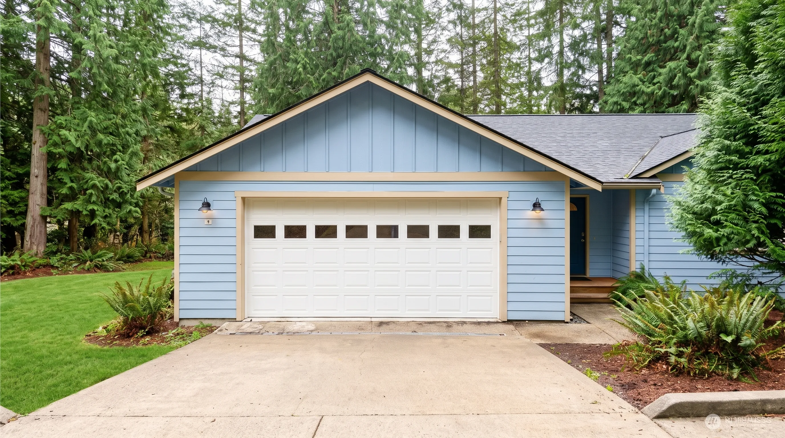 A single-story home with a pitched roof, set among evergreens on a quiet residential lot.